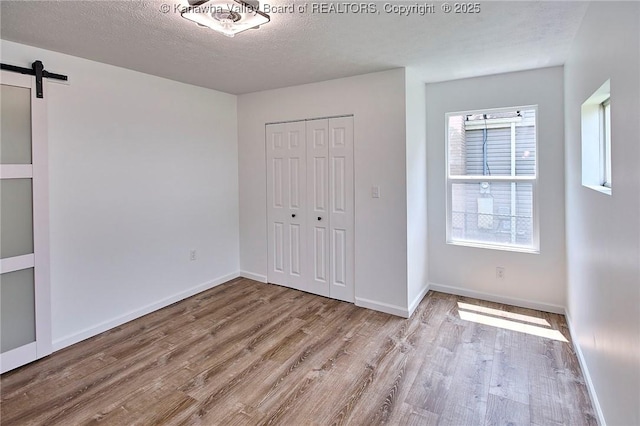 911 Dupont Ave, Nitro, WV 25143 - unfurnished bedroom featuring wood finished floors, a closet, a barn door, and a textured ceiling