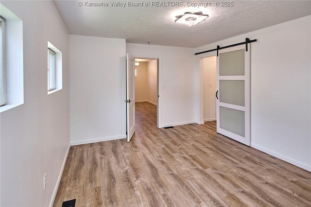 911 Dupont Ave, Nitro, WV 25143 - unfurnished bedroom featuring wood finished floors, a barn door, and a textured ceiling