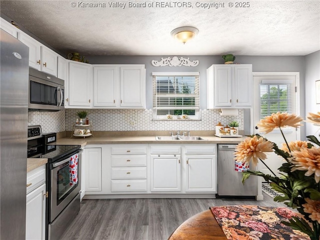 732 Jordan Pl, Nitro, WV 25143 - kitchen with stainless steel appliances, white cabinets, a textured ceiling, backsplash, and wood finished floors