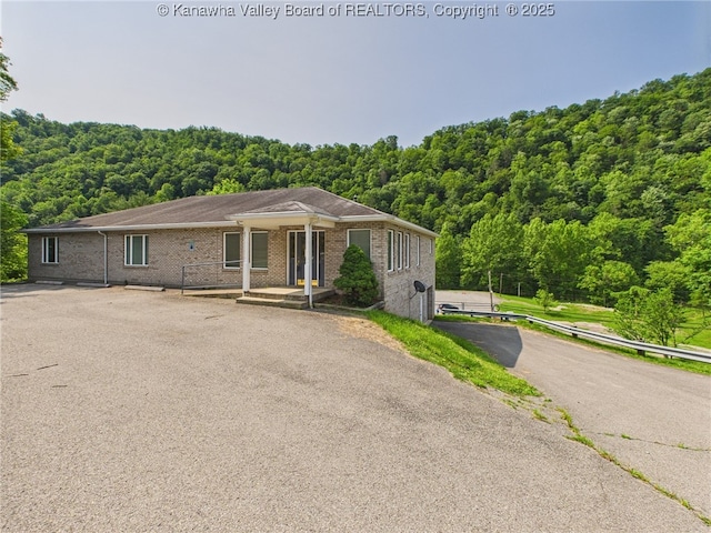 319 Main St, Clay, WV 25043 - view of front of property featuring a wooded view, brick siding, covered porch, and driveway