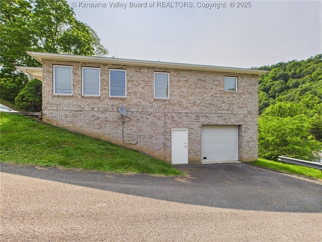 319 Main St, Clay, WV 25043 - view of side of property with an attached garage, asphalt driveway, and brick siding
