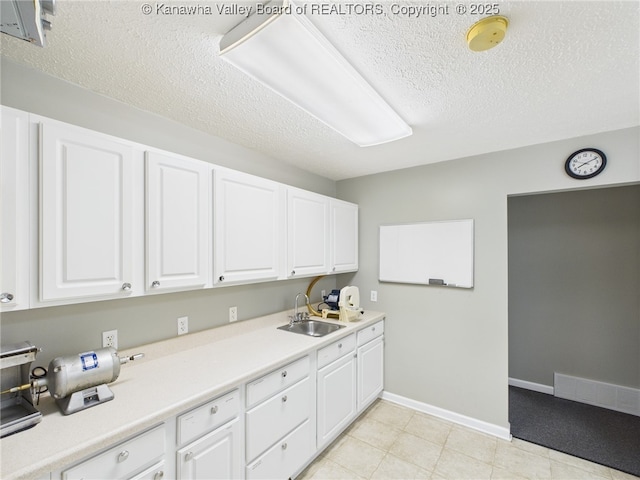 319 Main St, Clay, WV 25043 - kitchen featuring a textured ceiling, white cabinets, light countertops, and light tile patterned flooring
