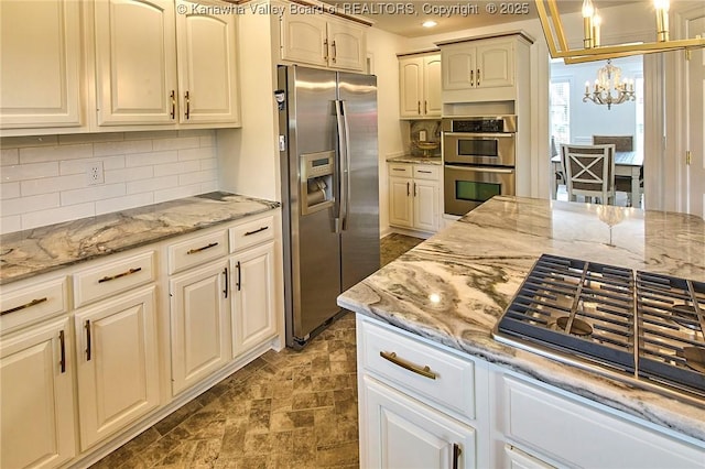 1004 Wethersfield Xing, Hurricane, WV 25526 - kitchen with appliances with stainless steel finishes, a chandelier, decorative backsplash, light stone countertops, and recessed lighting