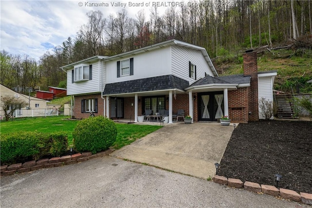 969 Airport Rd, Chapmanville, WV 25508 - view of front of house featuring brick siding, covered porch, driveway, and a front yard