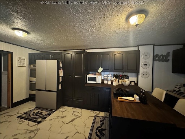 969 Airport Rd, Chapmanville, WV 25508 - kitchen with white microwave, stainless steel double oven, freestanding refrigerator, marble finish flooring, and a textured ceiling