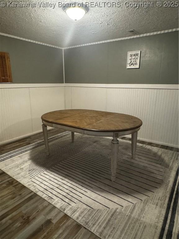 969 Airport Rd, Chapmanville, WV 25508 - dining space featuring wood finished floors, a textured ceiling, a decorative wall, and a wainscoted wall