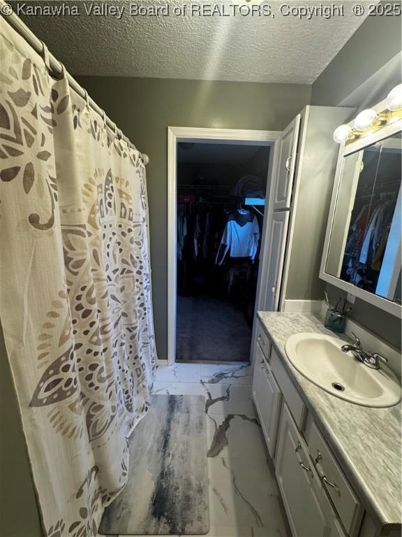 969 Airport Rd, Chapmanville, WV 25508 - full bath with marble finish flooring, vanity, a textured ceiling, and a walk in closet