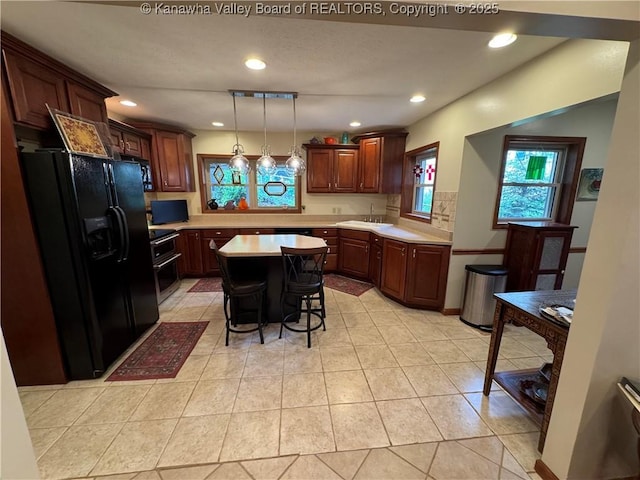 201 Sheridan Cir, Charleston, WV 24315 - kitchen featuring black refrigerator with ice dispenser, light countertops, recessed lighting, light tile patterned floors, and a breakfast bar area