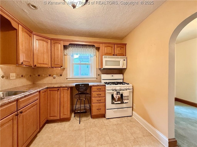 108 W Main St, Belle, WV 25015 - kitchen featuring white appliances, arched walkways, a textured ceiling, brown cabinetry, and decorative backsplash