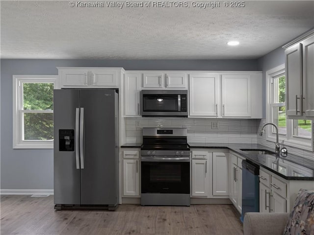 5285 Kelly Rd, Charleston, WV 25313 - kitchen with appliances with stainless steel finishes, a textured ceiling, dark countertops, light wood finished floors, and plenty of natural light