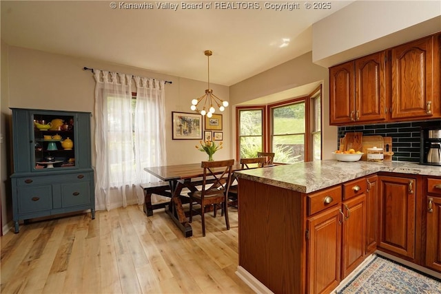 32 Carriage Rd, Charleston, WV 25314 - kitchen featuring light wood-style flooring, brown cabinetry, a chandelier, decorative light fixtures, and tasteful backsplash