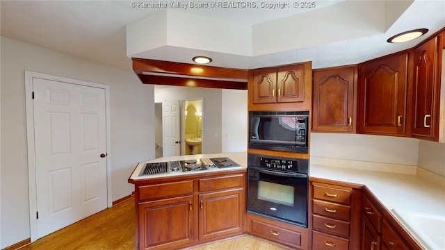 81 Hamill Rd, Huntington, WV 25701 - kitchen featuring black appliances, light countertops, light wood finished floors, a peninsula, and brown cabinets