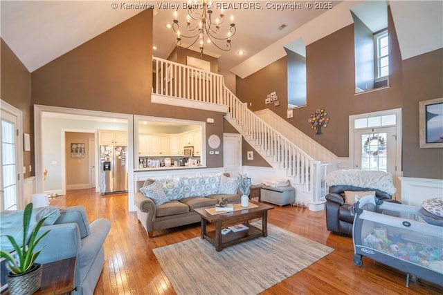 365 Tyler Way, Scott Depot, WV 25560 - living room featuring high vaulted ceiling, stairway, a chandelier, light wood-style floors, and a wainscoted wall