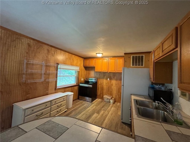 292 Maysel Laurel Ridge Rd, Wv, WV 25133 - kitchen with stainless steel electric range, wooden walls, freestanding refrigerator, light wood-style flooring, and tile countertops