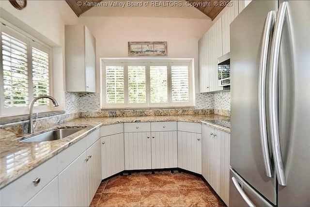 948 Little Coal River Rd, Alum Creek, WV 25003 - kitchen with stainless steel appliances, decorative backsplash, vaulted ceiling, light stone counters, and white cabinetry