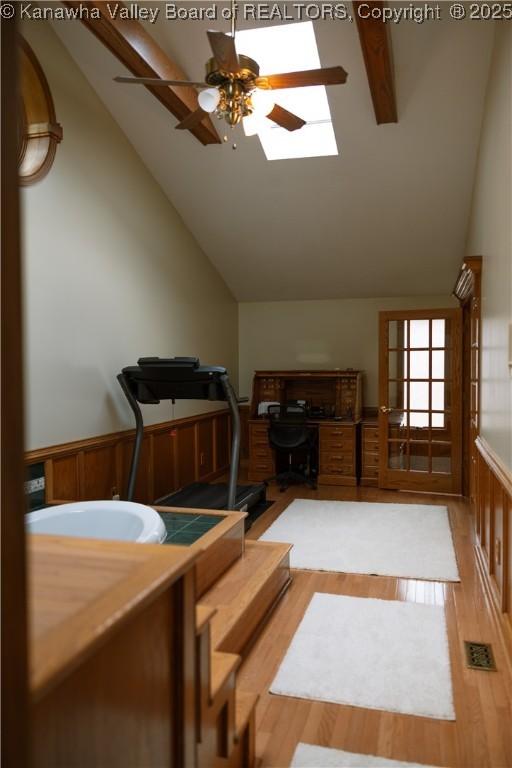 35 Belpac Cir, Logan, WV 25601 - exercise area with a ceiling fan, light wood-style floors, a skylight, high vaulted ceiling, and a wainscoted wall