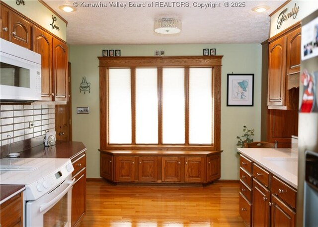 35 Belpac Cir, Logan, WV 25601 - kitchen featuring white appliances, light wood-style floors, tasteful backsplash, brown cabinetry, and a textured ceiling