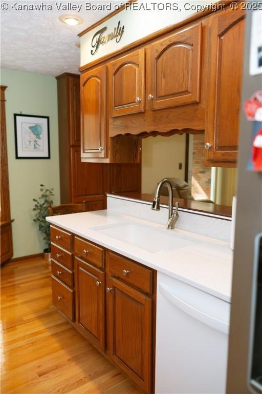 35 Belpac Cir, Logan, WV 25601 - kitchen featuring dishwasher, brown cabinets, light countertops, a textured ceiling, and light wood finished floors