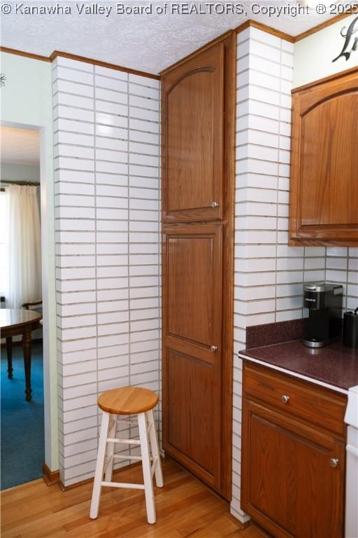 35 Belpac Cir, Logan, WV 25601 - kitchen with crown molding, brown cabinetry, dark countertops, and light wood-style flooring