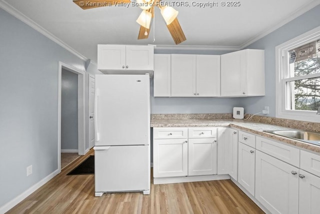 528 Medina St, Charleston, WV 25302 - kitchen with freestanding refrigerator, ornamental molding, light wood-style floors, white cabinets, and light countertops