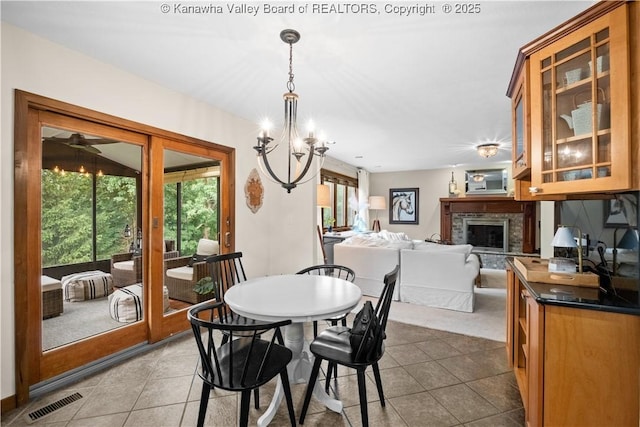 137 Summit Ridge Rd, Hurricane, WV 25526 - dining room featuring a chandelier, tile patterned flooring, a fireplace with raised hearth, and a ceiling fan