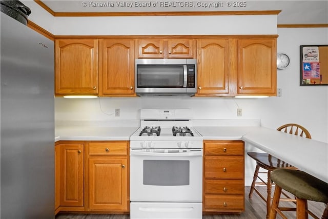 733 Divide Ridge Rd, Given, WV 25245 - kitchen with appliances with stainless steel finishes, light countertops, wood finished floors, ornamental molding, and brown cabinetry