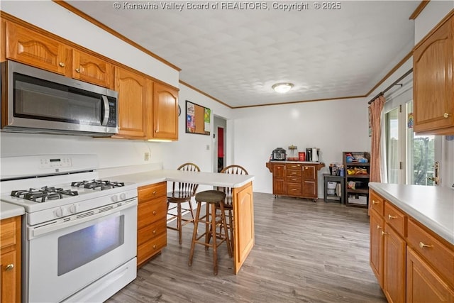733 Divide Ridge Rd, Given, WV 25245 - kitchen with stainless steel microwave, white gas range, a kitchen breakfast bar, crown molding, and light countertops