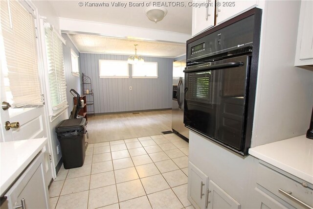 4312 Lancaster Ave, Charleston, WV 25304 - kitchen featuring black oven, white cabinetry, a chandelier, light tile patterned flooring, and decorative light fixtures