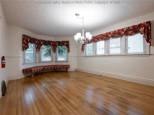 623 11th Ave, Huntington, WV 25701 - empty room featuring light wood finished floors, a chandelier, healthy amount of natural light, and a textured ceiling