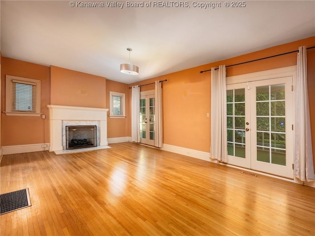 623 11th Ave, Huntington, WV 25701 - unfurnished living room with french doors, light wood-style flooring, and a premium fireplace