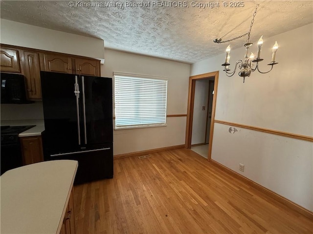 448 18th St, Dunbar, WV 25064 - kitchen featuring black appliances, a textured ceiling, light wood-style flooring, a chandelier, and light countertops