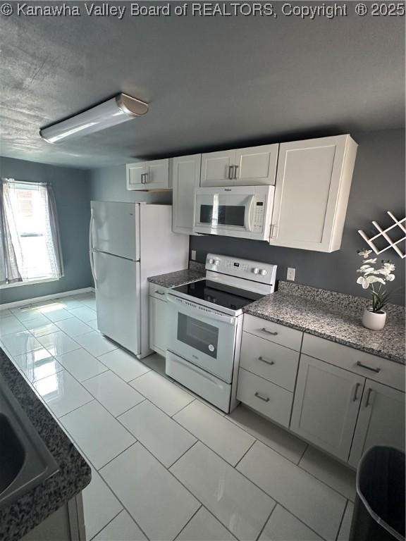 1110 Benamati Ave, Nitro, WV 25143 - kitchen with white appliances, white cabinets, light tile patterned floors, and stone counters