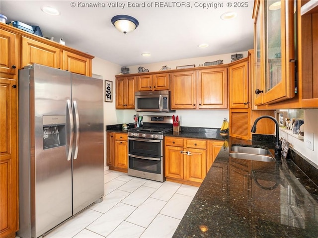 1105 Hollyberry Ln, South Charleston, WV 25309 - kitchen with stainless steel appliances, brown cabinets, dark stone countertops, and glass insert cabinets