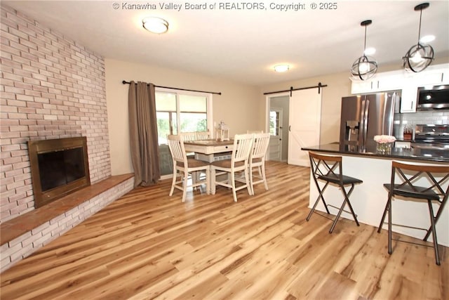 1412 Wilkie Dr, Charleston, WV 25314 - dining space featuring a barn door, light wood-type flooring, and a fireplace