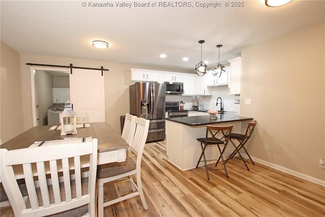 1412 Wilkie Dr, Charleston, WV 25314 - kitchen with stainless steel appliances, a barn door, a peninsula, light wood-style floors, and white cabinets