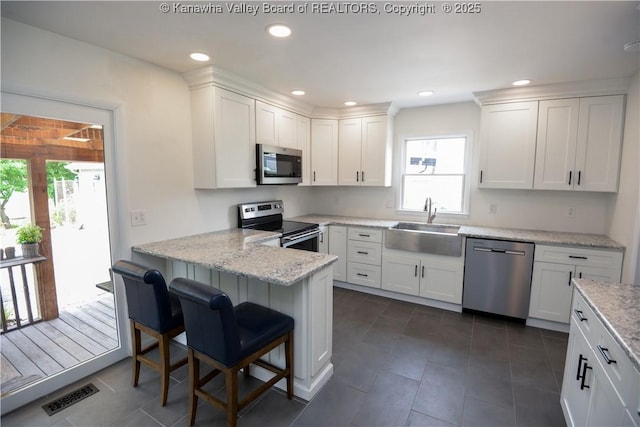 1516 Fenton Cir, Nitro, WV 25143 - kitchen with stainless steel appliances, a peninsula, white cabinetry, a kitchen breakfast bar, and dark tile patterned flooring