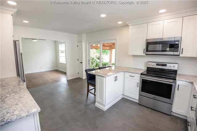 1516 Fenton Cir, Nitro, WV 25143 - kitchen with stainless steel appliances, a peninsula, white cabinets, a kitchen bar, and recessed lighting