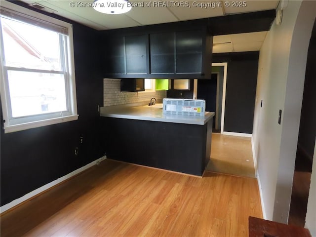 4808 Kentucky St, South Charleston, WV 25309 - kitchen with dark cabinetry, a peninsula, light wood-style flooring, decorative backsplash, and light countertops