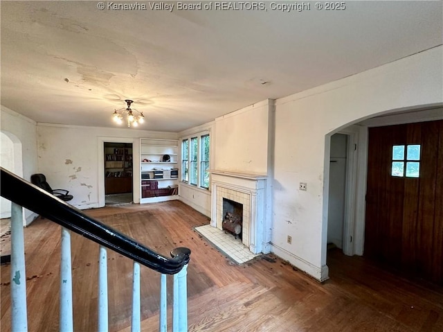 5430 Virginia Ave SE, Charleston, WV 25304 - unfurnished living room featuring a tiled fireplace, arched walkways, built in shelves, a chandelier, and wood finished floors