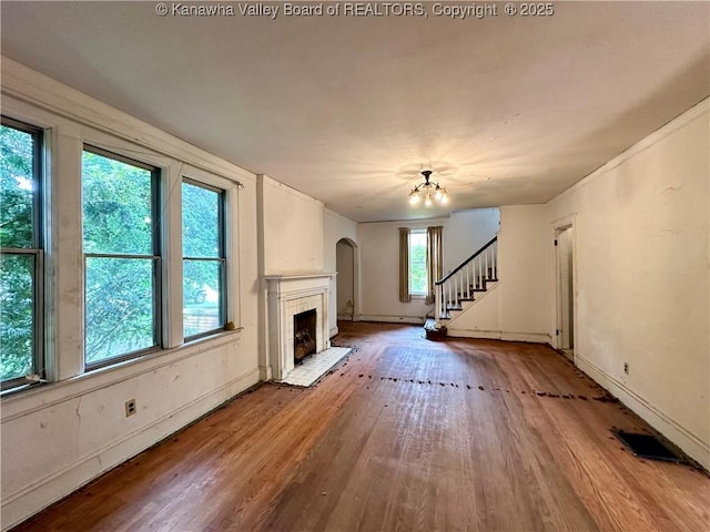 5430 Virginia Ave SE, Charleston, WV 25304 - unfurnished living room with wood finished floors, a tile fireplace, a chandelier, stairway, and arched walkways
