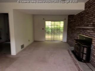 873 Woods Dr, Saint Albans, WV 25177 - unfurnished living room with a wood stove, carpet flooring, and brick wall
