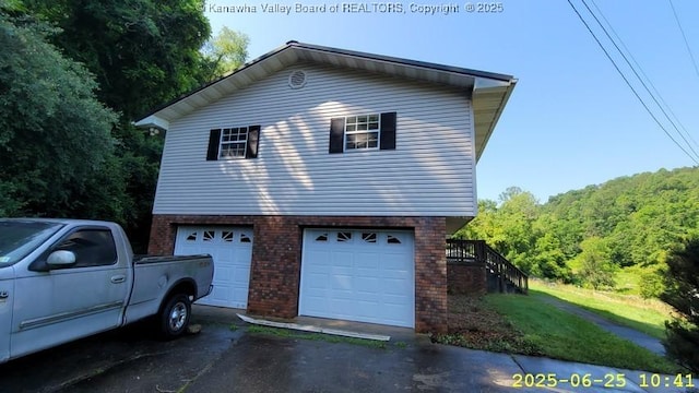 873 Woods Dr, Saint Albans, WV 25177 - view of property exterior featuring brick siding, asphalt driveway, an attached garage, and a wooded view