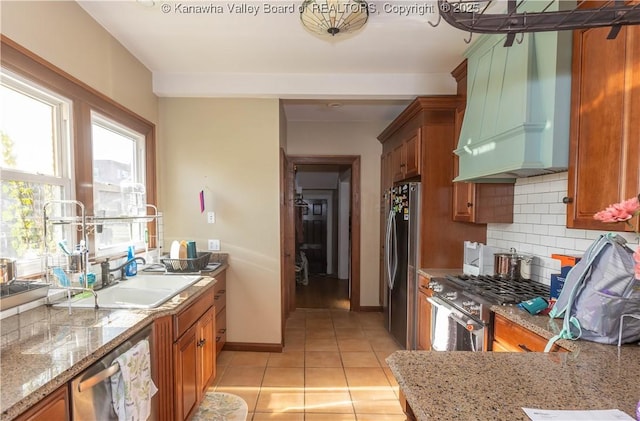 1212 10th St, Huntington, WV 25701 - kitchen with custom exhaust hood, stainless steel appliances, brown cabinets, tasteful backsplash, and light tile patterned flooring