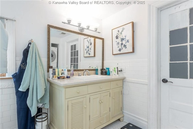 1212 10th St, Huntington, WV 25701 - bathroom with stacked washer / drying machine, tile walls, vanity, and a wainscoted wall