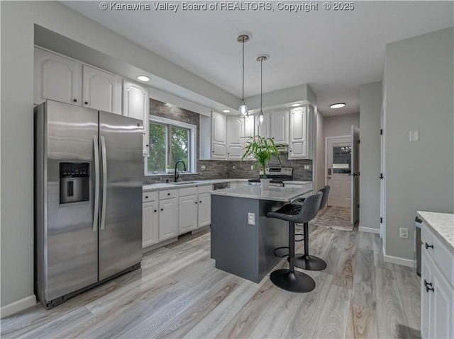 1437 Statts Mills Rd, Ripley, WV 25271 - kitchen featuring appliances with stainless steel finishes, white cabinets, a breakfast bar area, decorative backsplash, and hanging light fixtures