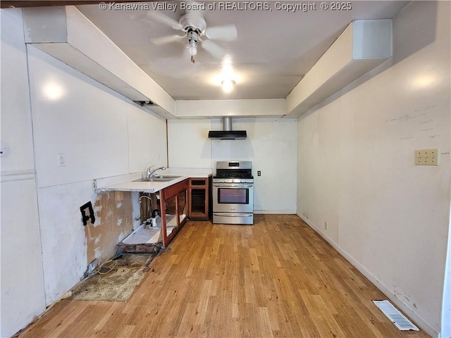 807 Honeysuckle Rd, Elkview, WV 25071 - kitchen featuring stainless steel gas stove, light wood-style flooring, ceiling fan, light countertops, and wall chimney exhaust hood