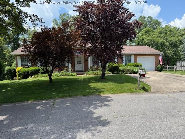 2234 Circle Dr, Milton, WV 25541 - view of property hidden behind natural elements with concrete driveway, a front lawn, and an attached garage