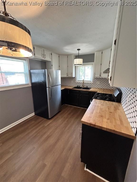 2010 Preston St, Charleston, WV 25302 - kitchen with freestanding refrigerator, black range with gas stovetop, decorative backsplash, dark wood-style floors, and wood counters