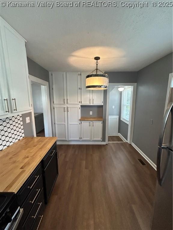 2010 Preston St, Charleston, WV 25302 - kitchen featuring appliances with stainless steel finishes, white cabinets, wooden counters, dark wood-type flooring, and hanging light fixtures