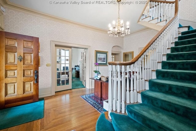 1598 Kanawha Blvd E, Charleston, WV 25311 - entrance foyer featuring wallpapered walls, crown molding, arched walkways, a chandelier, and stairs
